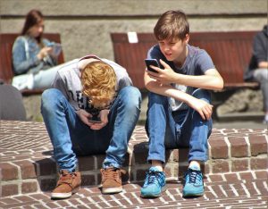 Children outside, all looking at smartphone screens.