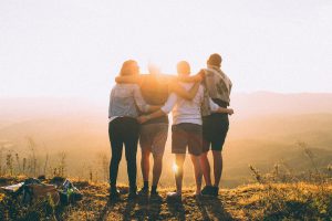 Friends watching sunset - arms around each other