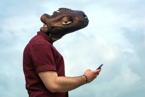 Montage of person with Toothless's head, holding a smartphone, looking at viewer cynically